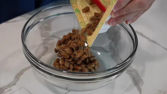 Stir the natto with chopsticks to lighten its texture. You can eat it as is, but stirring makes it fluffier.