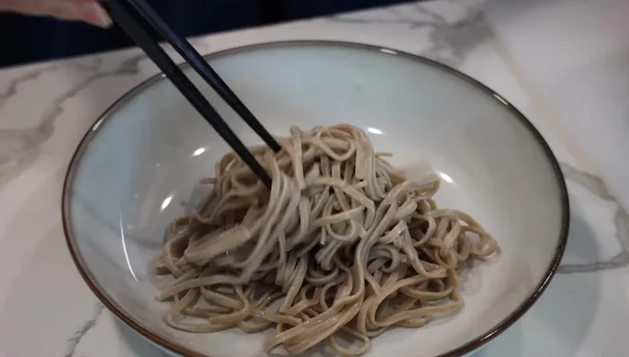 On a serving dish, place the cooked soba noodles. Top with natto, grated yam, okra, green onions, and egg yolk.