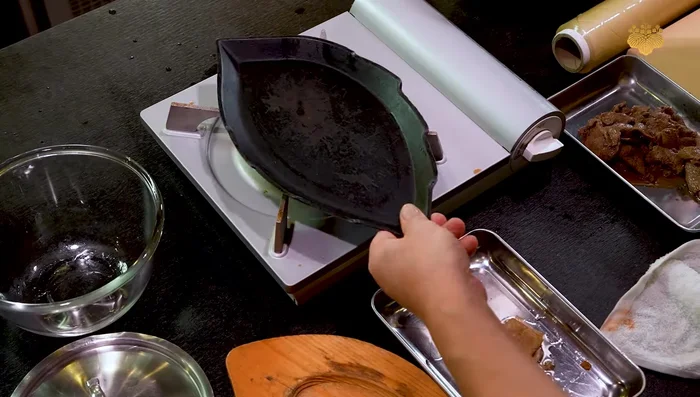 Assemble the dish in a heated cast iron skillet (or regular pan): Add half of the fried beef, kinshi tamago strips, chopped green onions, remaining marinade, and repeat layers. Garnish with lemon slices, daikon radish with aka roshi paste, and nori.