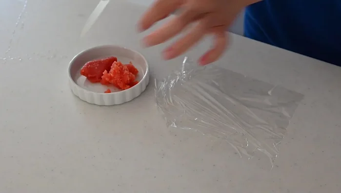 Remove the skin from the tarako and take out the roe inside. Place the roe onto plastic wrap, cut open the skin, and scrape out the roe.