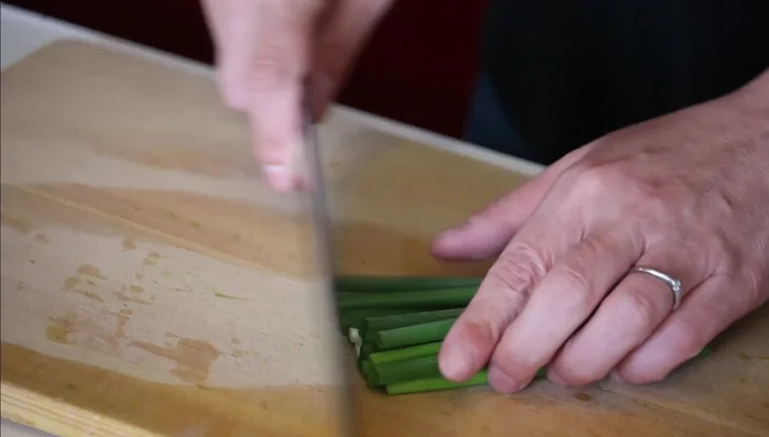Prepare the green onions: Cut off the bottom, halve them lengthwise, then thinly slice. Set aside in a bowl for garnish. (50.48)