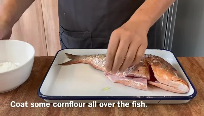Remove marinade ingredients, coat fish liberally with corn flour, patting it down. Let it rest for one minute, then repeat on the other side.