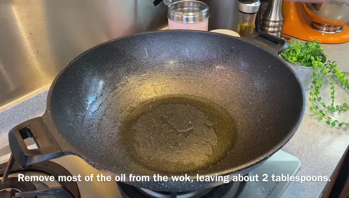 In the same wok, remove most of the oil, leaving about 2 tbsp. Add chopped ginger and garlic, stir-fry briefly until fragrant.
