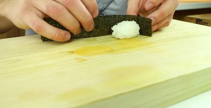 Place the nori strip on a sushi rolling mat, mat-side inwards. Wrap the rice around the nori.