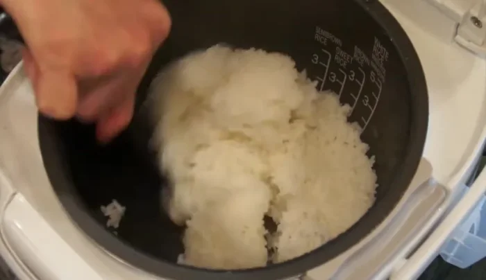 Once the rice is cooked, fluff it with a cutting motion. (154.14, 276.37) Gently mix the sautéed ingredients into the rice. (158.16, 279.25)