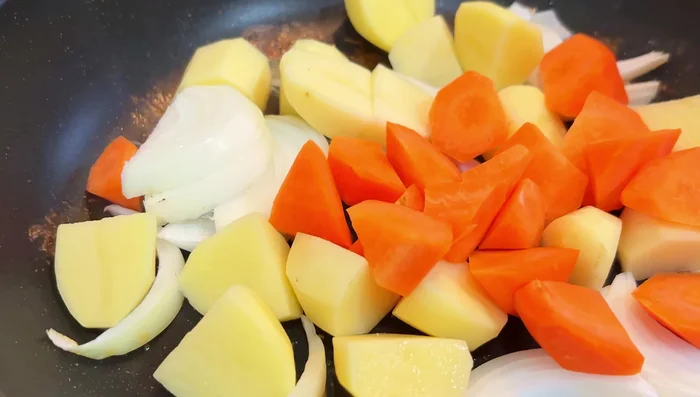 Add onions, carrots, and potatoes to the pan. Sauté, adding a splash of water if needed to deglaze the pan.