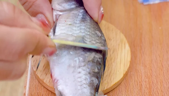 Prepare the fish: scale, trim fins, and score the body.