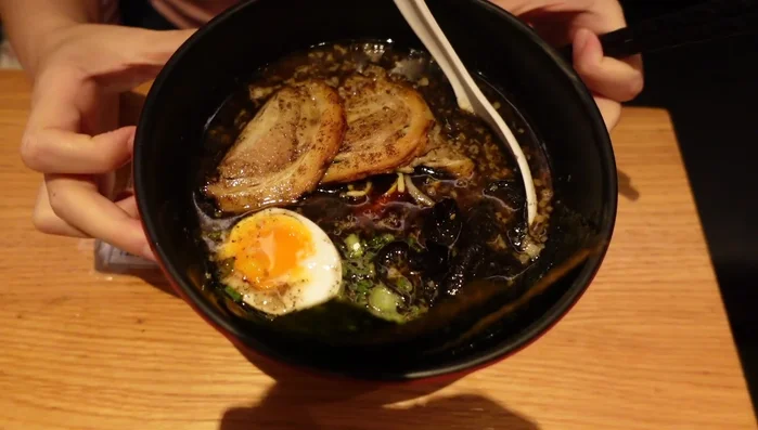 Prepare the soup base. The speaker mentions a miso or bean paste as a key ingredient, along with a spicy oil. The exact proportions are not specified in the transcript.