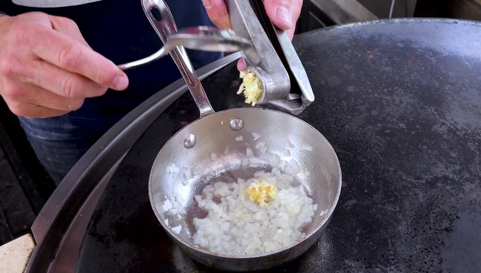 Add minced garlic to the sauce and cook briefly.
