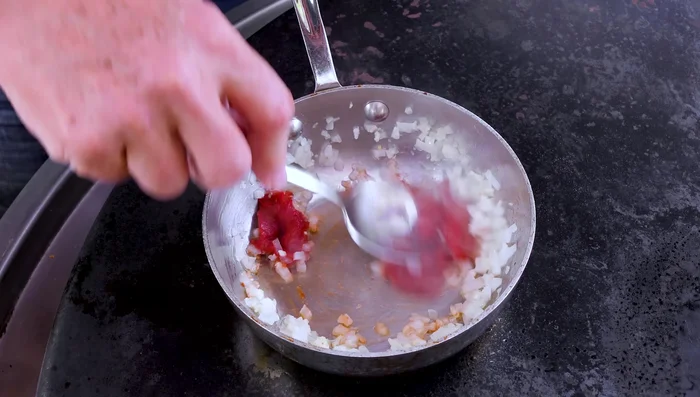 Stir in tomato paste and anchovy paste, cooking until fragrant.