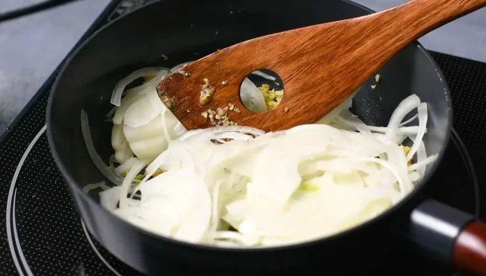 Add thinly sliced onions and caramelize for about 30 minutes, adding water halfway through to prevent sticking.