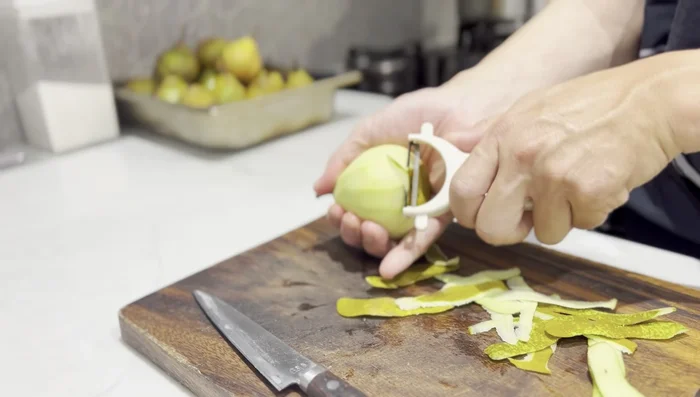 Immediately drop the peeled pears into the light syrup to prevent discoloration.