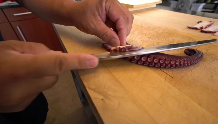 Assemble the nigiri: Place a portion of sushi rice in your hand, gently shaping it into an oval. Add a piece of octopus to the rice, carefully pressing it to adhere. (193.49)