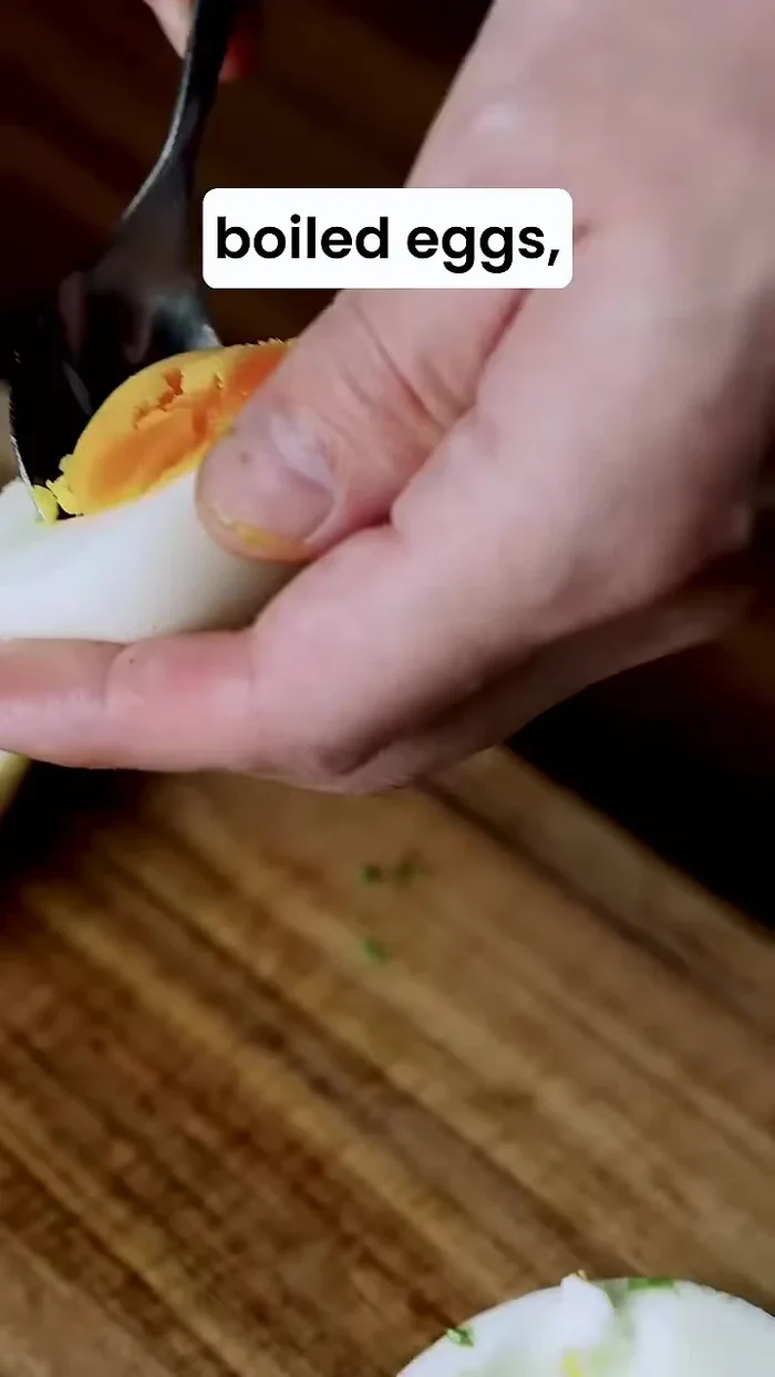Scoop out the yolks of two boiled eggs and add them to the bowl.