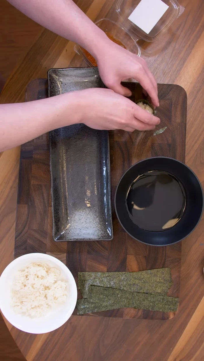 Assemble the Gunkan: Wrap the rice log with the prepared nori, ensuring about three-quarters of the band is covered by the rice.