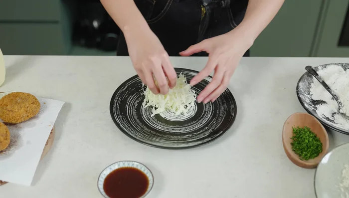 Serve the Menchi Katsu with cabbage and katsu sauce.