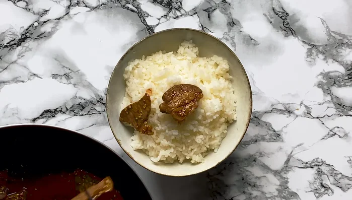 Turn off the heat. Remove the meat from the pan using tongs or chopsticks and place it on top of the rice.