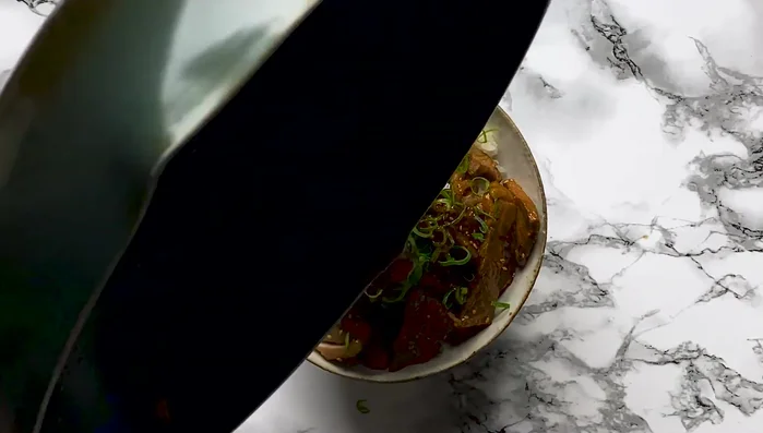 Garnish with spring onion and drizzle the leftover sauce over the meat.