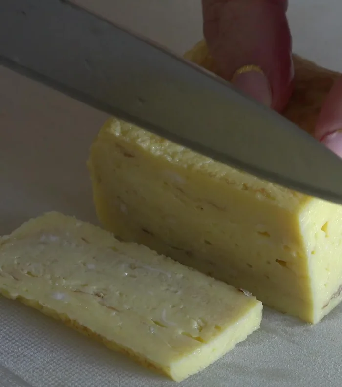 Prepare Tamagoyaki: Slice the rolled omelette.