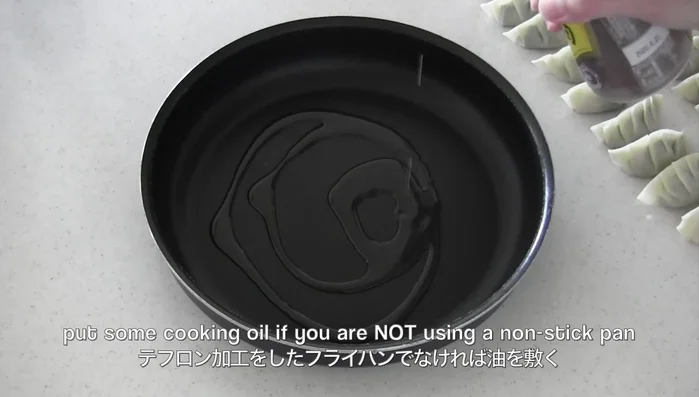 Heat cooking oil in a pan. Place gyoza in the pan.