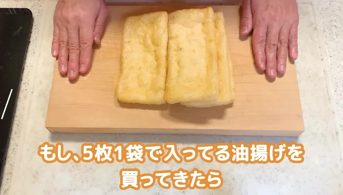 Prepare the fried tofu by blotting excess oil with kitchen paper. Press the tofu and fold it in half, then twist one end to create a hollow pouch. Cut in half.