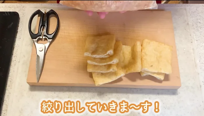 Squeeze the enoki mushroom mixture from the plastic bag into the prepared fried tofu pouches. Use spaghetti to close the pouches.