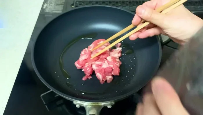 Fry the pork: Add the pork to the hot pan, wait a bit before stirring to achieve a nice brown color. Break the pork into smaller pieces for even browning.