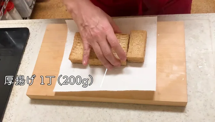 Remove excess oil from the deep-fried tofu using kitchen paper. Gently tear the tofu into smaller pieces.