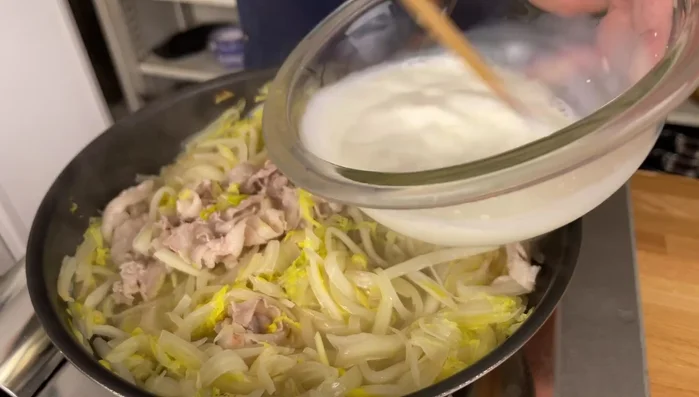 Once the cabbage is softened and the liquid reduced, add the milk-potato starch mixture while stirring continuously to prevent lumps from forming. Simmer until thickened.