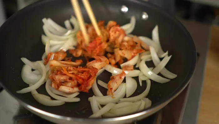 Add the kimchi to the onions and stir-fry until fragrant.
