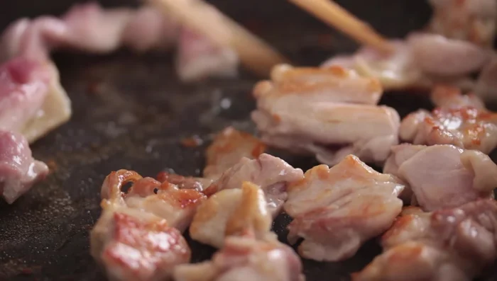 Flip the chicken and cook the other side. Push the cooked chicken to one side of the pan.