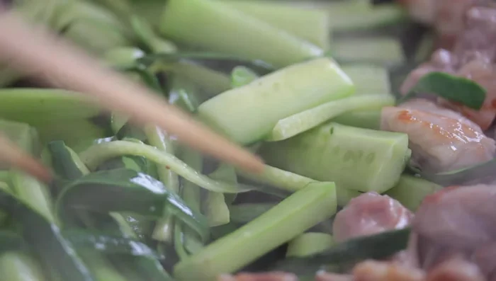 Add the cucumber pieces (flesh, skin, and seeds separately if desired), garlic, and chili pepper (if using) to the chicken oil and stir-fry for about 1.5 minutes.