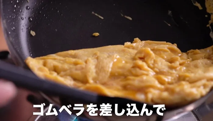 Continue cooking, gently pushing the cooked egg to one side and tilting the pan to allow the uncooked egg to cook. The tamagoyaki will naturally roll up as it cooks.