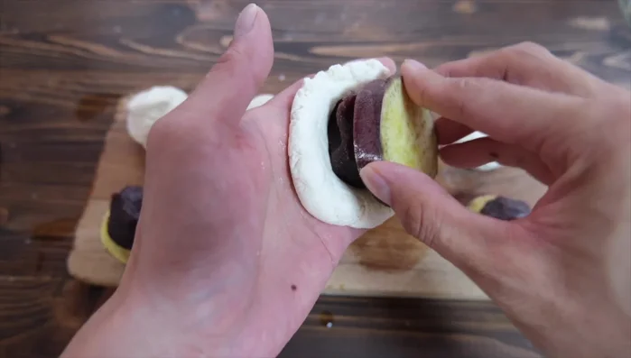 Flatten the dough, wrap it around the sweet potato and bean paste, sealing it tightly.