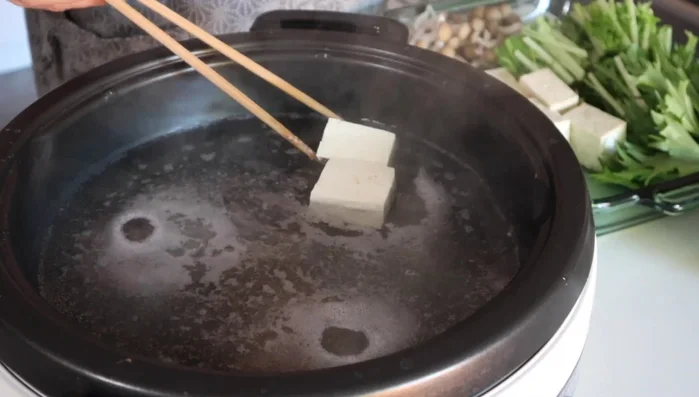 Add tofu and vegetables to the broth.