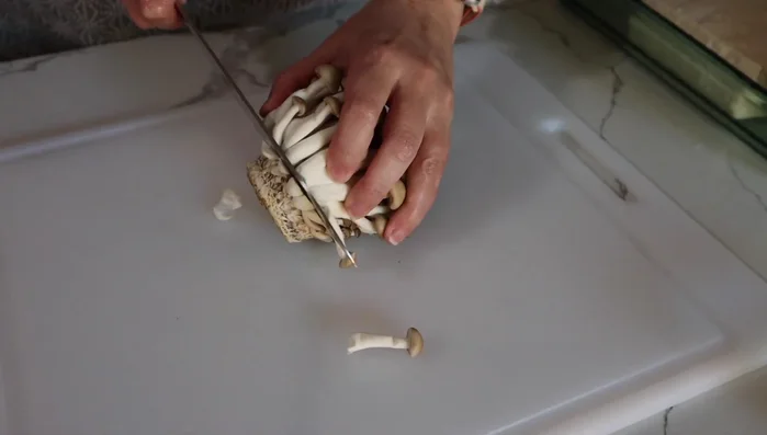 Cut off the ends of shimeji mushrooms and separate into small bunches.