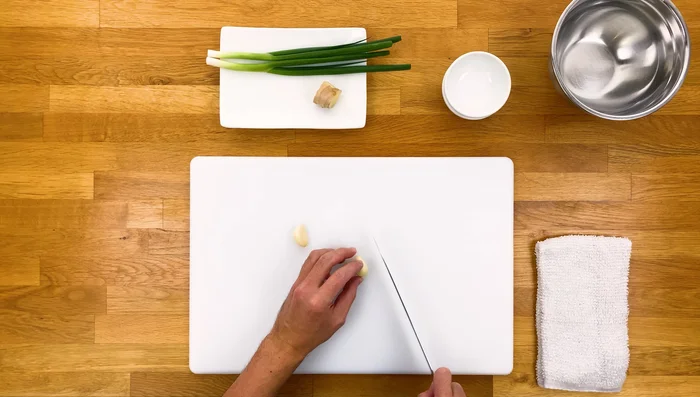 Mince garlic, julienne ginger, and thinly slice green onions (using only the green parts). Place green onions in an ice bath for a few minutes.
