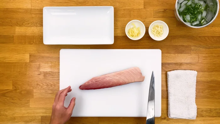 Cut Hamachi into thin sashimi slices against the grain (approximately 1/4 inch thick).
