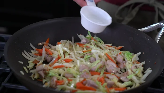 Add 1/3 cup of water, cover, and let it steam to cook the ingredients and soften the cabbage.