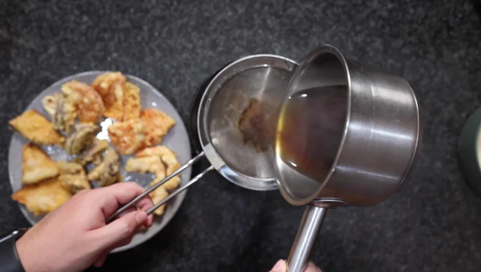 Assemble the dish: Place cooked udon noodles in a bowl. Pour the heated udon soup over the noodles, straining out any Bonito flakes. Arrange the tempura on top. Garnish with chopped green onions.