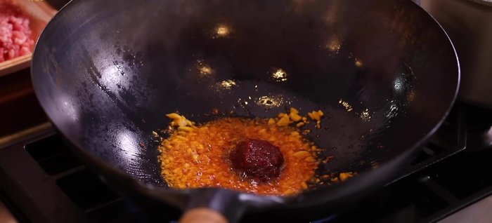 Add doubanjiang, oyster sauce, and ground pork to the wok. Stir-fry until the meat is cooked through. Add cooking wine and deglaze the wok.