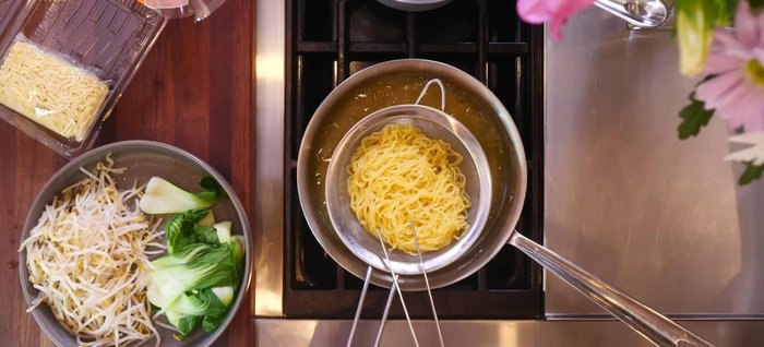 Add the cooked noodles to the bowl, coating them with the broth.
