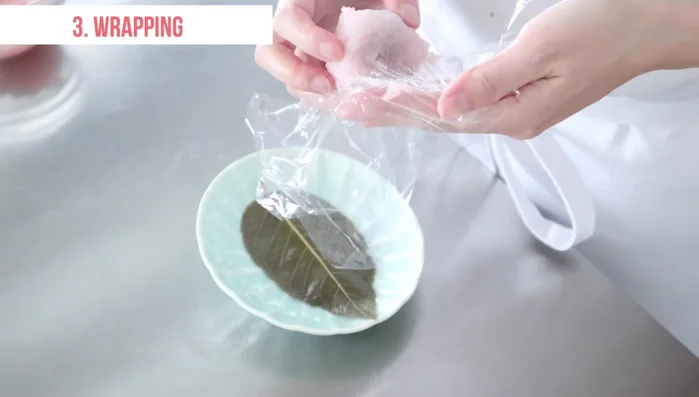 Pat dry the sakura leaves and place them on a plate. Serve the mochi on a leaf and make incisions on top. Garnish with a strawberry.