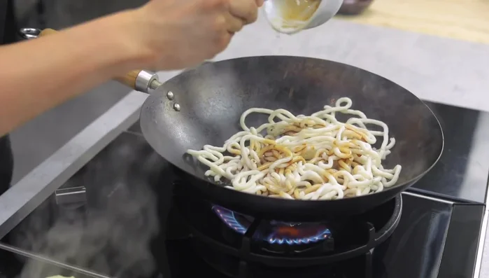 Pour the stir-fry sauce (light soy sauce, sugar, tonkatsu sauce, sesame oil) over the noodles.