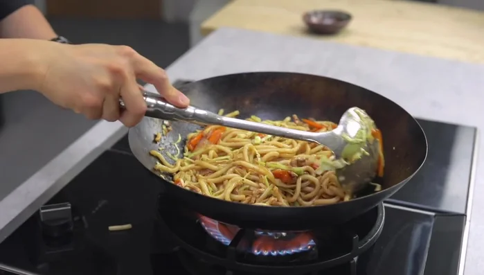 Continue stir-frying until the noodles are almost sticking to the wok but not burning.