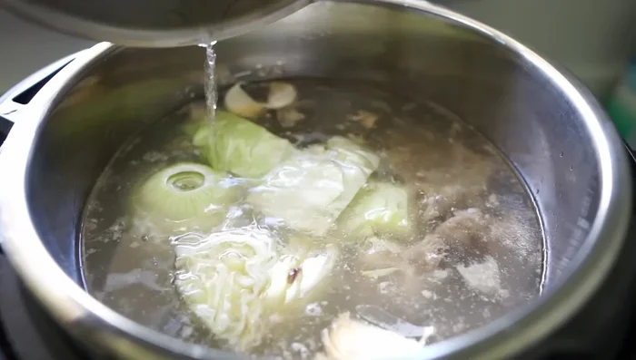 Naturally release pressure, then add water, aromatics (onion, garlic, cabbage), and simmer uncovered for 1 hour, stirring occasionally.