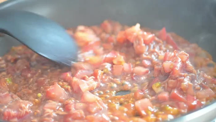 In a separate pan, cook the tomato mixture, adding water initially. Simmer until the tomatoes soften. Then, thicken the sauce by gradually adding a water-dissolved potato starch mixture until it reaches a desired consistency.