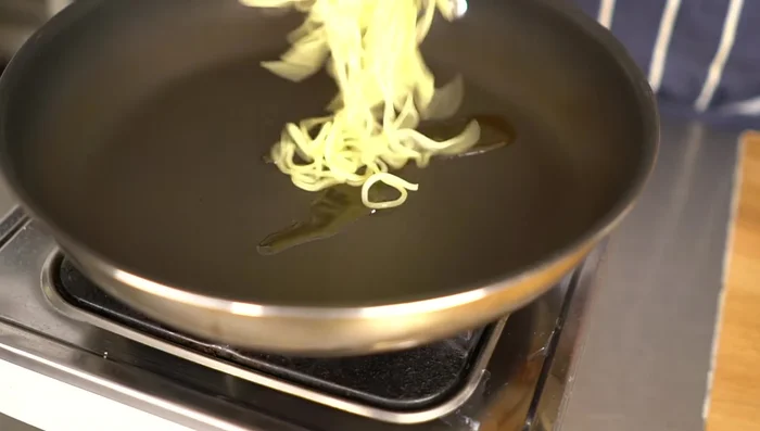 Heat sesame oil in a frying pan. Add the noodles and break them apart, frying until lightly browned on one side. Then flip and cook the other side until crispy.