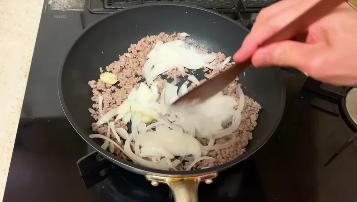 Once the minced meat is cooked, add the onions and cook until softened.