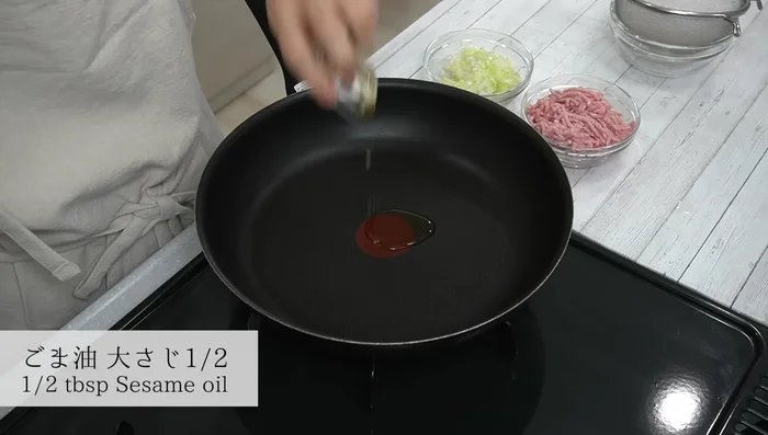 Heat sesame oil in a frying pan, add minced garlic and ginger, and stir-fry until fragrant.